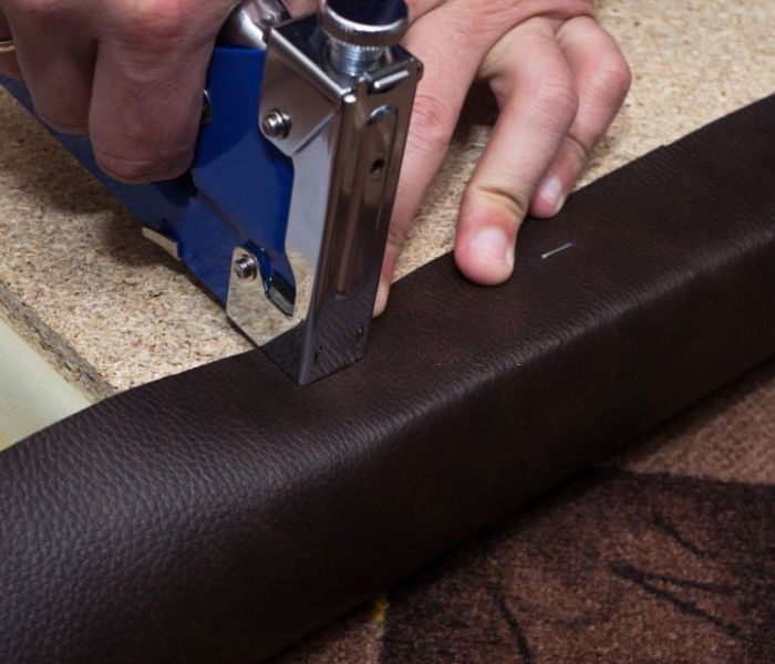 Craftsman fastening leather to the paricle board